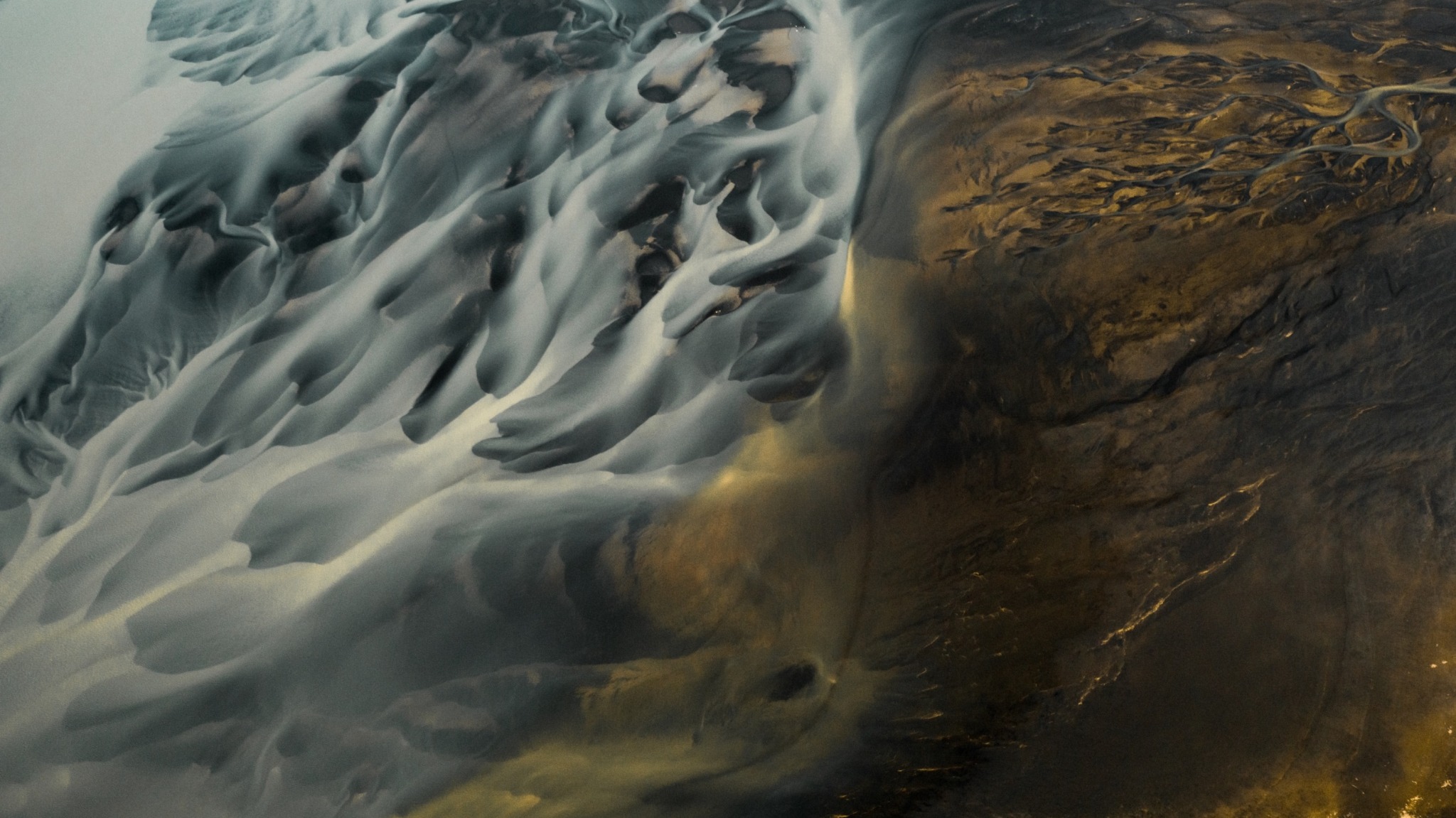 Aerial landscape with flowing patterns in muted teal and gold